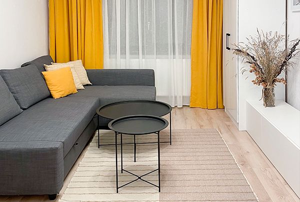 Vizigon renovation of a 43 sqm apartment living room with grey corner sofa and yellow curtains
